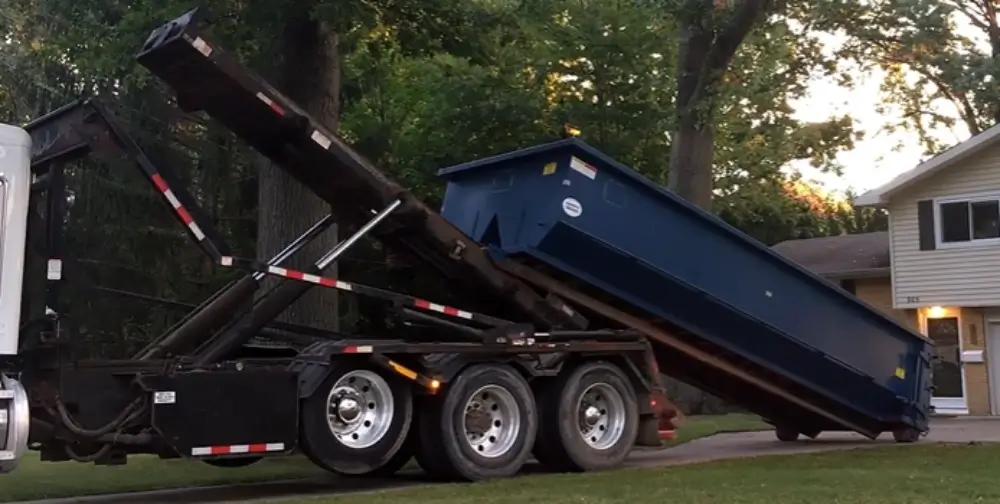 Dumpster being delivered via roll-off truck