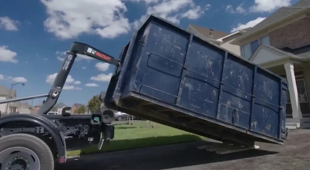 Dumpster being lifted by hooklift truck
