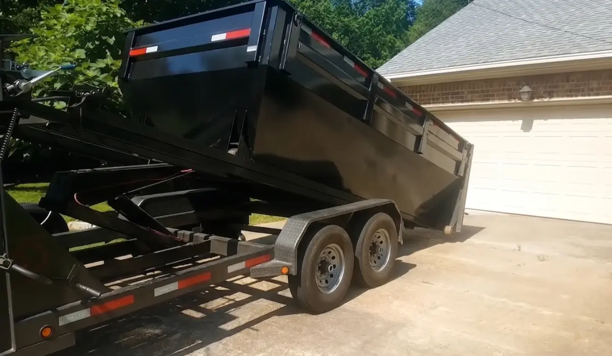 Black roll-off dumpster on a delivery trailer parked in a driveway, Sarasota FL
