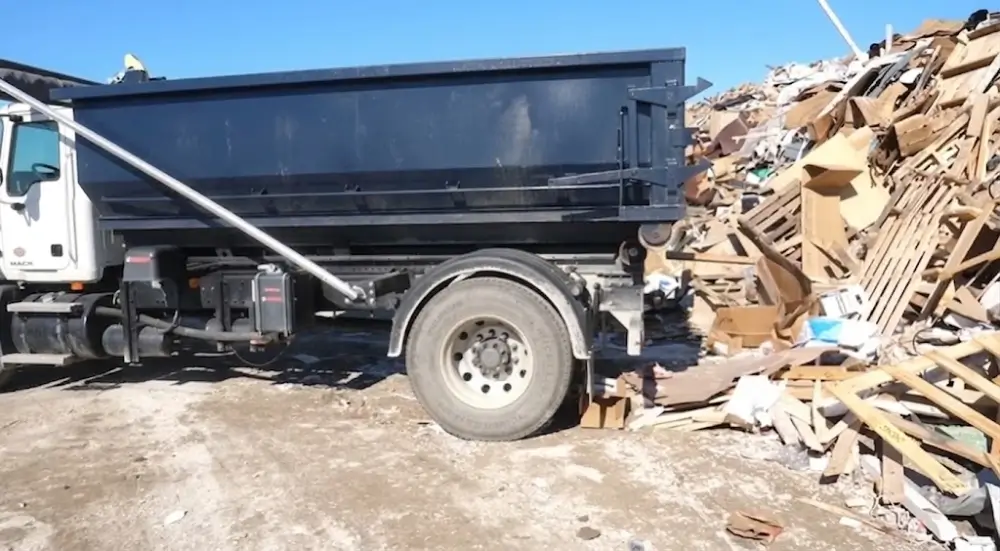 Roll-off dumpster at recycling facility wood pile