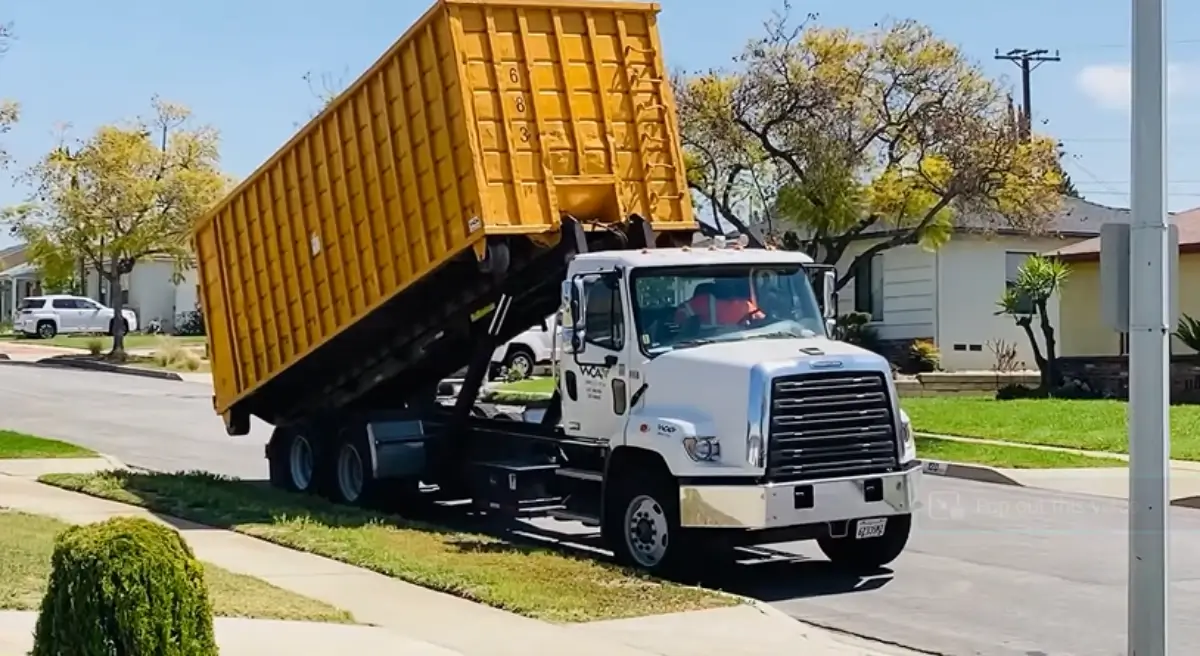 Roll-off truck tilting and unloading a dumpster onto a Sarasota FL residential street