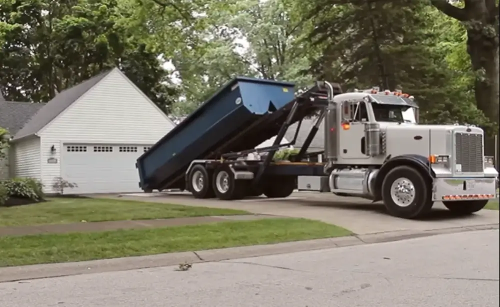 Silver Peterbilt truck delivering dumpster